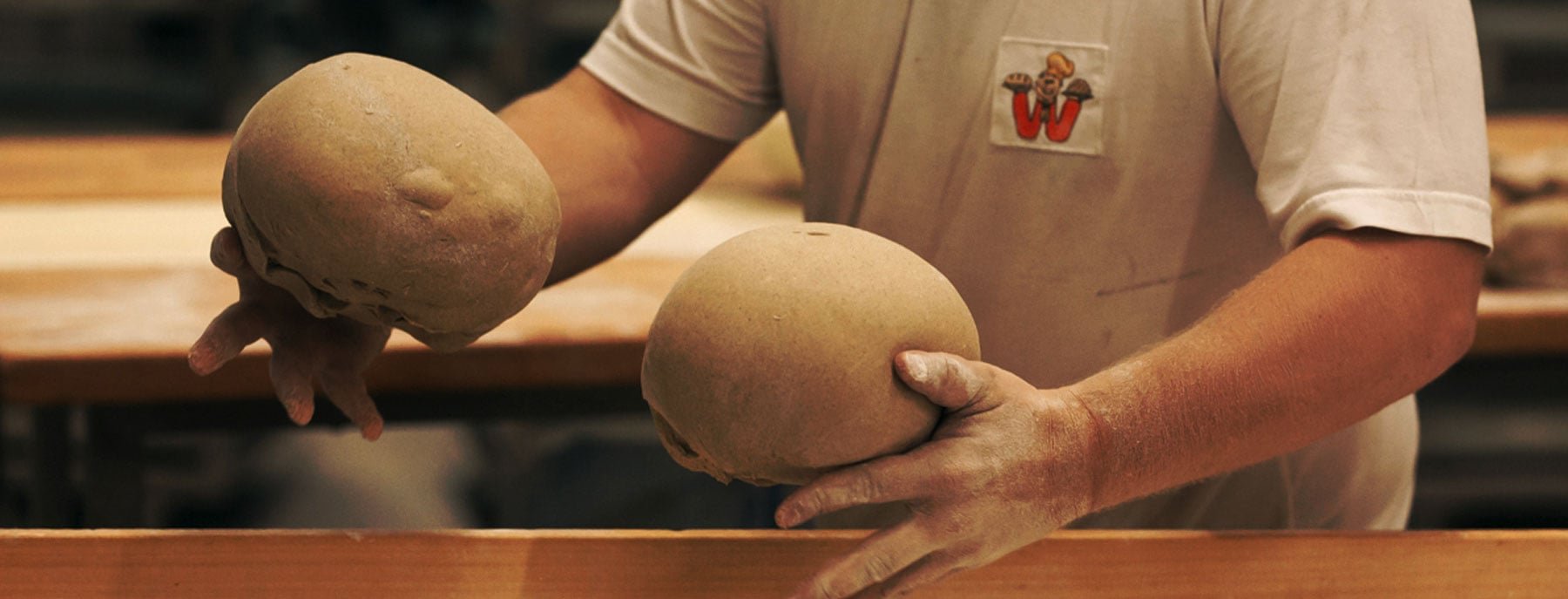 Ein Bäcker knetet zwei Teigstücke