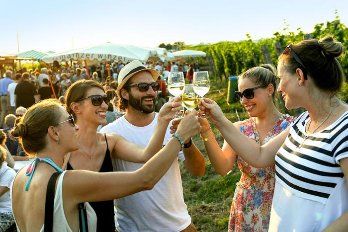 Menschen stoßen im Weinberg mit Weißwein an